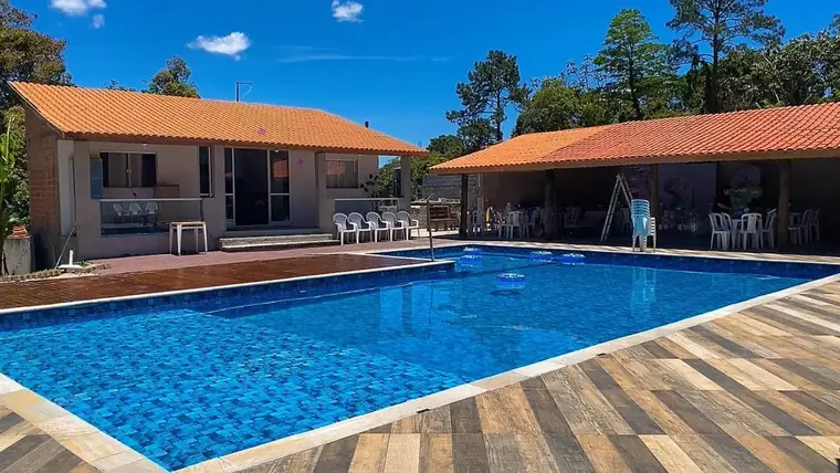 Área coberta com mesas e cadeiras ao lado da piscina